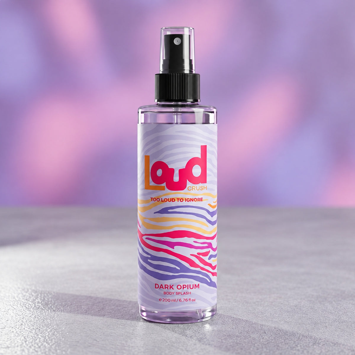 A clear spray bottle of Loud Drum 'Dark Opium' room spray with a black spray top and a colorful label featuring pink, purple, yellow, and white wavy stripes, set against a soft purple and pink blurred background.